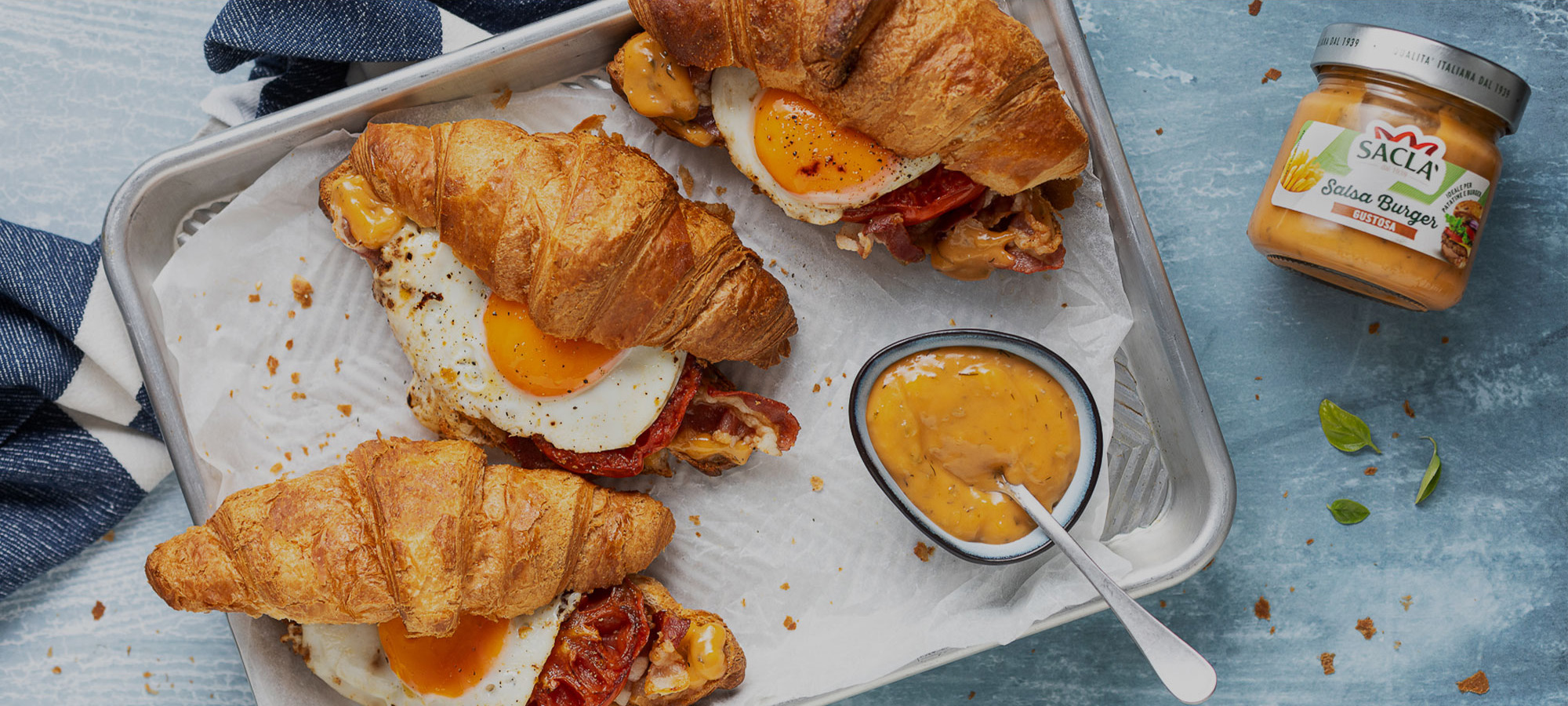 Toast di croissant con Salsa Burger Saclà, bacon, pomodoro e uova al tegamino